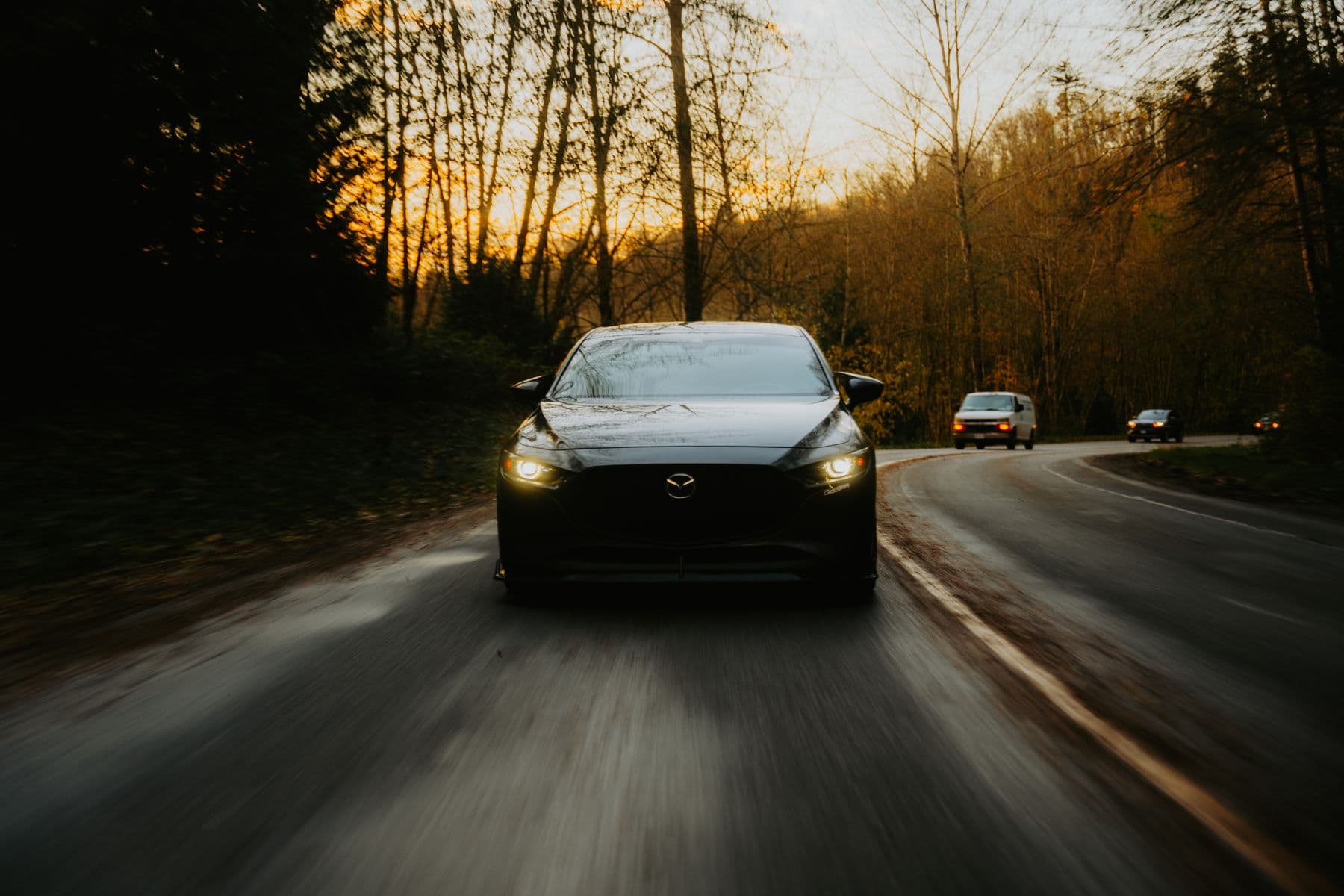 A car travelling along a winding road through autumn woodland